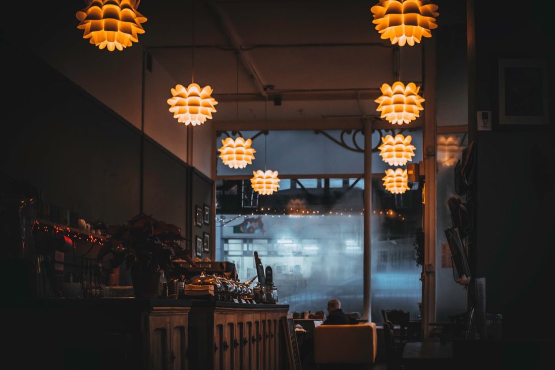 The dining room at dusk, pendant lamps glowing against the front window