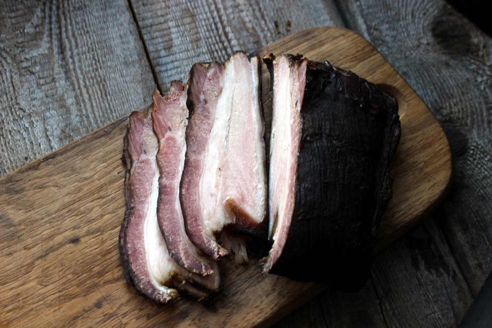 Alder-smoked pork belly sliced on a worn cutting board